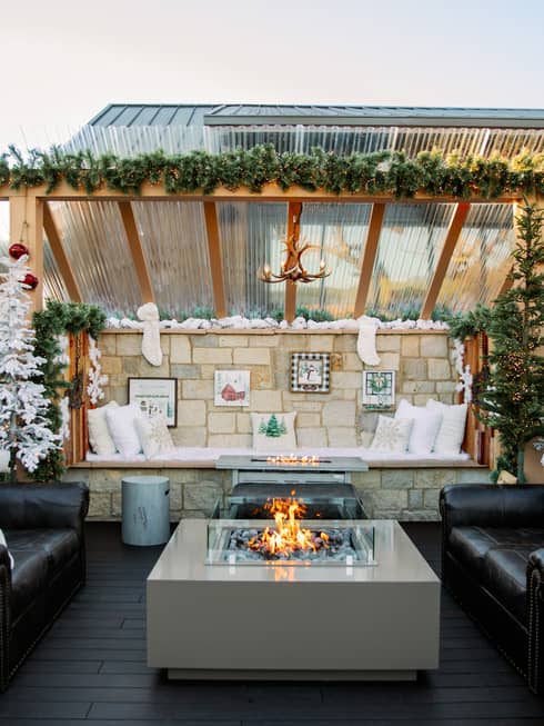 Outdoor terrace with two couches and a fire pit, and festive decorations.