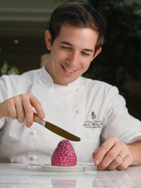 Chef Nicolas Lambert holding small knife, icing berry-shaped dessert