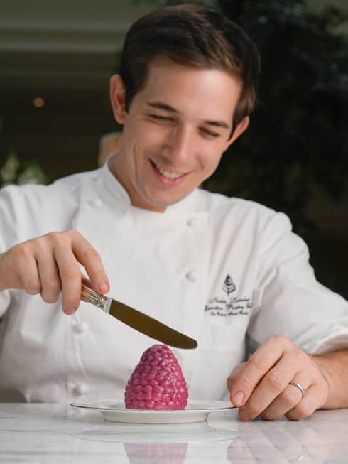 Chef Nicolas Lambert holding small knife, icing berry-shaped dessert