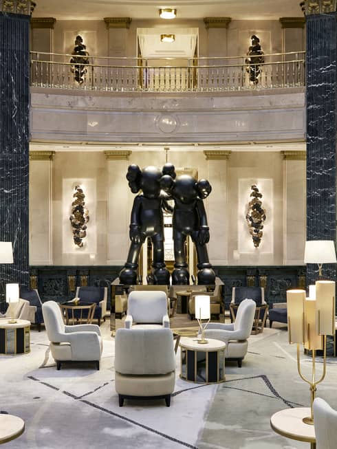 A spacious hotel lobby with a large seating area, black marble columns and a statue