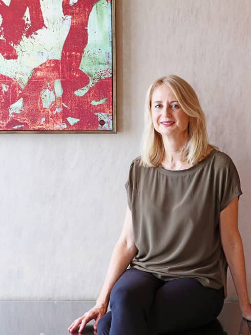 Kate Whitehead, a TRE specialist at Four Seasons Hong Kong, sits on a chair with artwork hanging on a wall