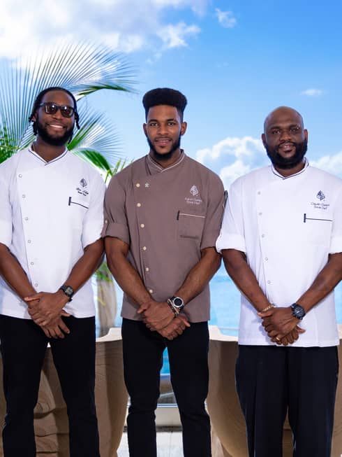 Staff members stand in a line in front of a blue-sky backdrop