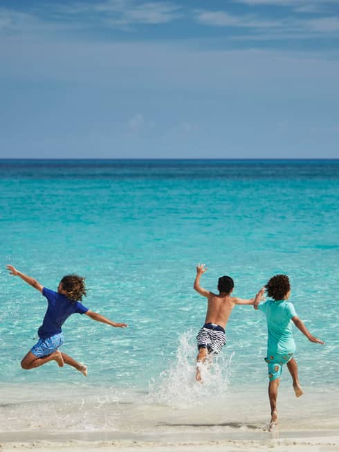 Children running into water from a beach.