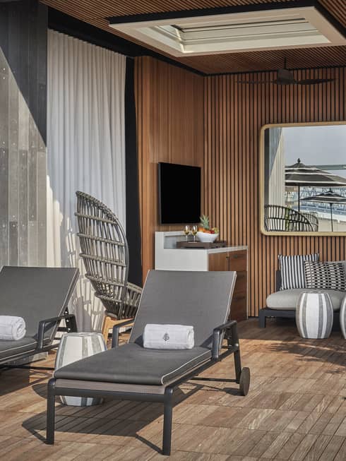 A cabana with two lounge chairs a sofa and plants.