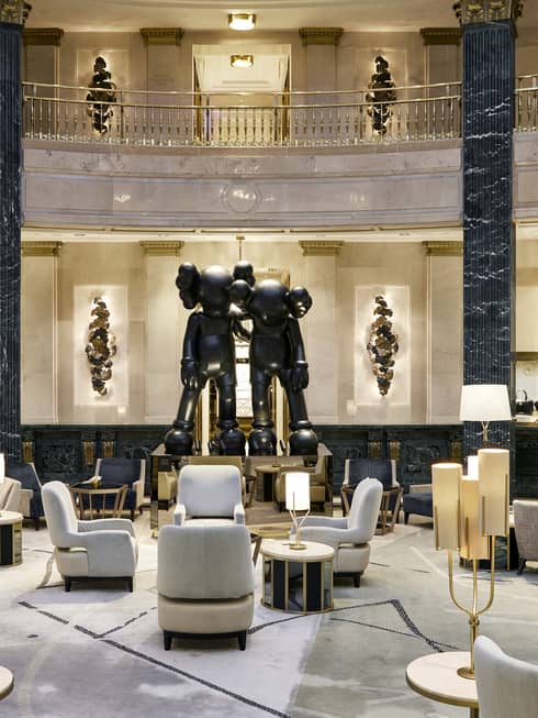 A spacious hotel lobby with a large seating area, black marble columns and a statue
