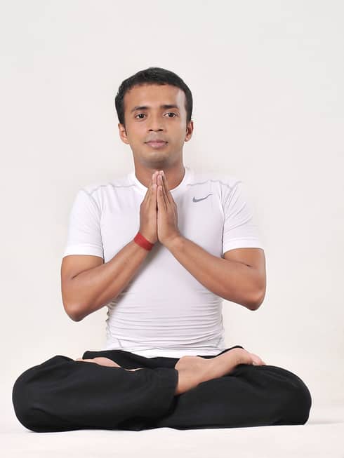 Yoga instructor Prabir Podder seated with legs crossed and hands in prayer pose