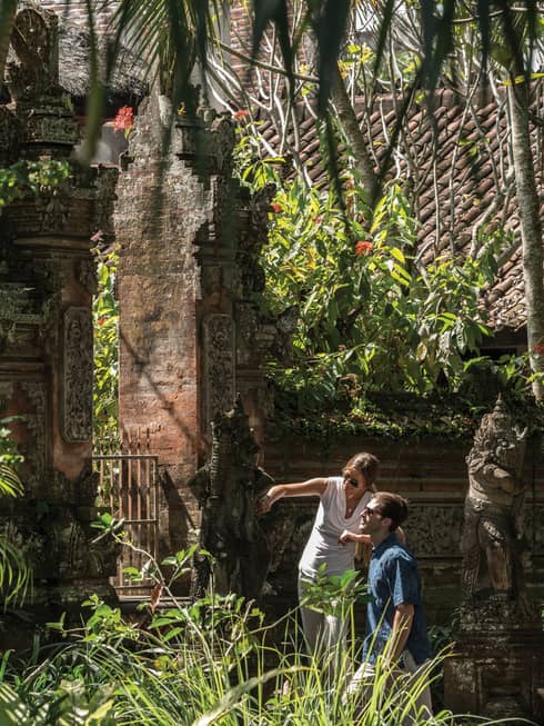 Gusts exploring decorative statues surrounding a temple in Bali