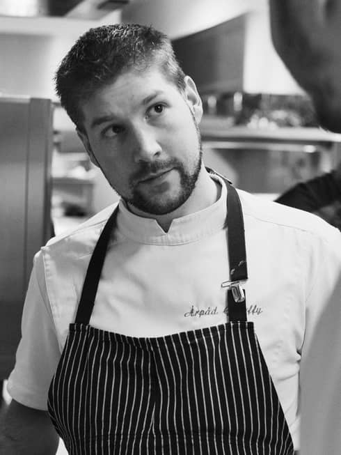Black-and-white portrait photo of Chef Arpád Győrffy in striped apron