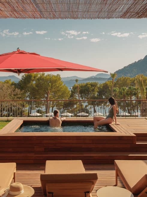 A man and woman relax in a private plunge pool overlooking sea