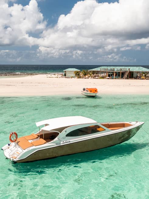 Brown and white boat in the ocean near a sandbar.