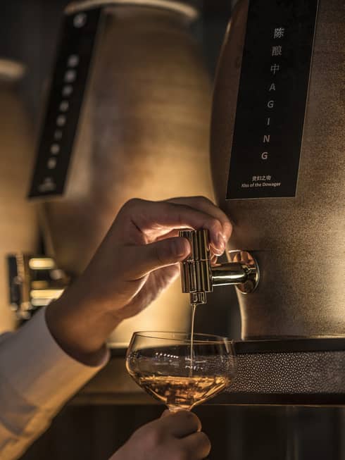 Close-up of bartender pouring liquor from tap into cocktail glass