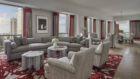 A living area with a large sofa, two chairs and large windows. inside a luxury suite in New Orleans
