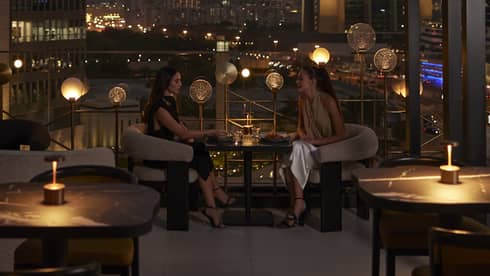 Nightime view of rooftop lounge with Dubai skyline in background