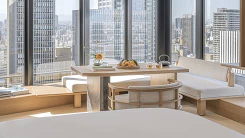 Luxurious guest room at Four Seasons Hotel Osaka with skyline views, modern decor, and serene seating area.