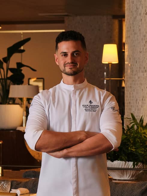 A chef stands in an elegant, softly lit indoor dining space.