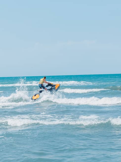 Person riding jet ski along waves in blue ocean