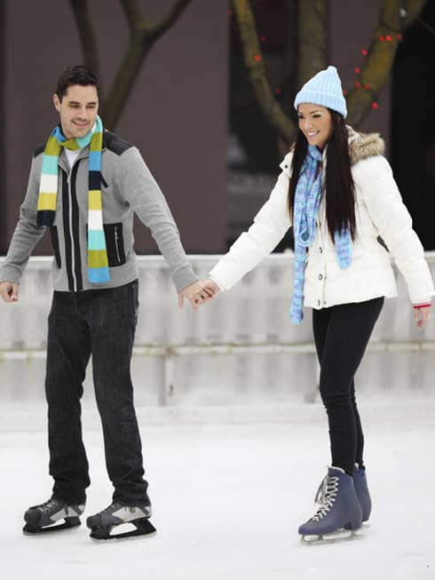 Couple wearing winter coats, hats and scarves ice skating