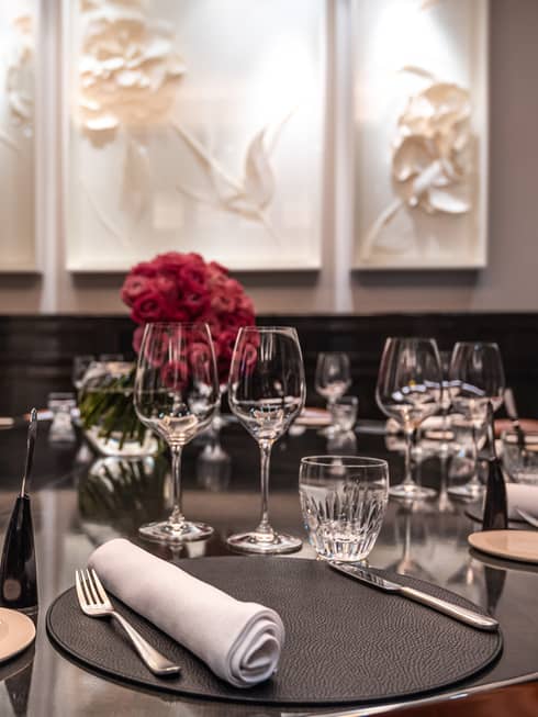 La Dame is ready for guests with round tables set with crystal, white napkins, tableware