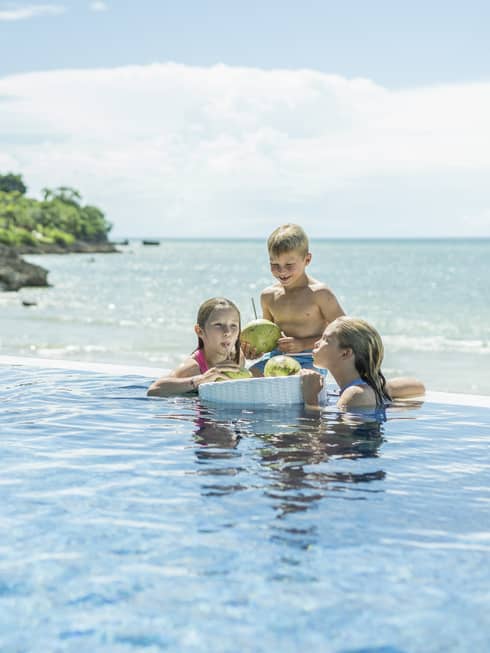 Two girls and a boy relax in the wading pool by the beach
