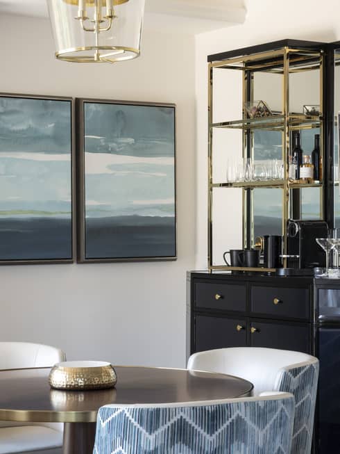 Guest room with round table and four blue chairs, wooden cocktail sidebar, and blue wall decor
