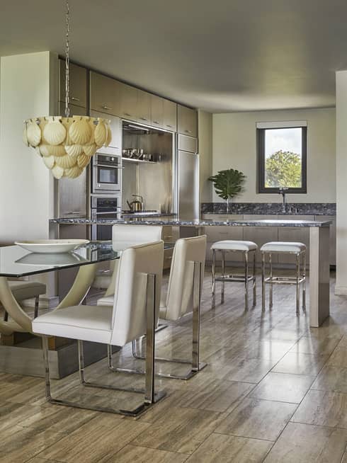 Three-bedroom penthouse dining room with glass table, white chairs, round white mirror, shell chandelier