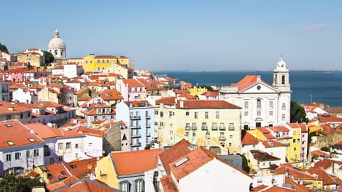 Aerial view of Lisbon skyline and rooftops on sunny day white houses, apartment buildings with brown roofs, white church
