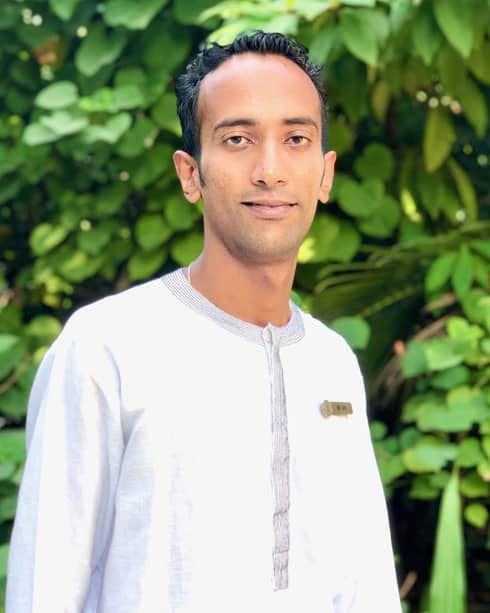 A smiling Dr. Giri in front of some greenery