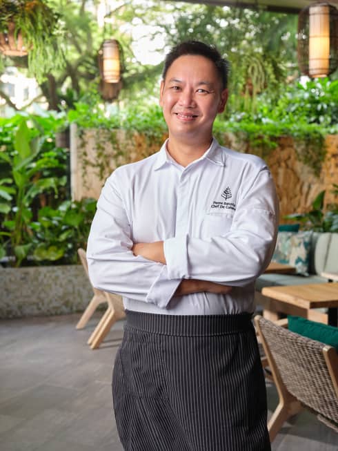 A smiling Chef de cuisine Pierre Barusta poses with his arms crossed at Garden@OneNinety