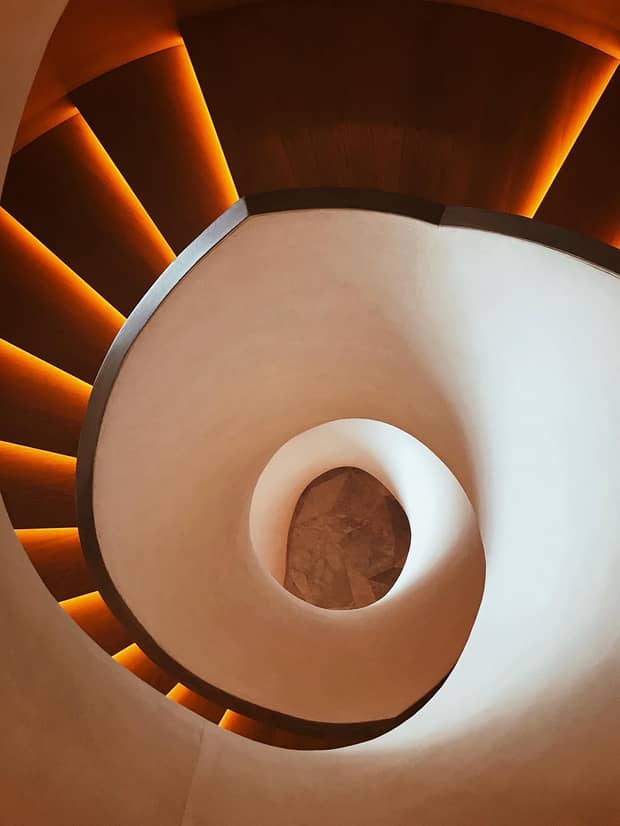 looking down into the center of a spiraling staircase with a smooth white exterior