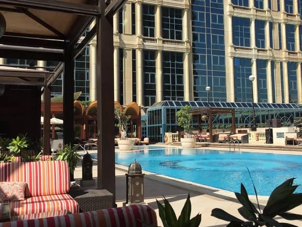 Striped patio sofa by sunny outdoor swimming pool, deck under building