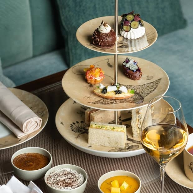 A tiered plate filled with various petits fours served with a glass of champagne