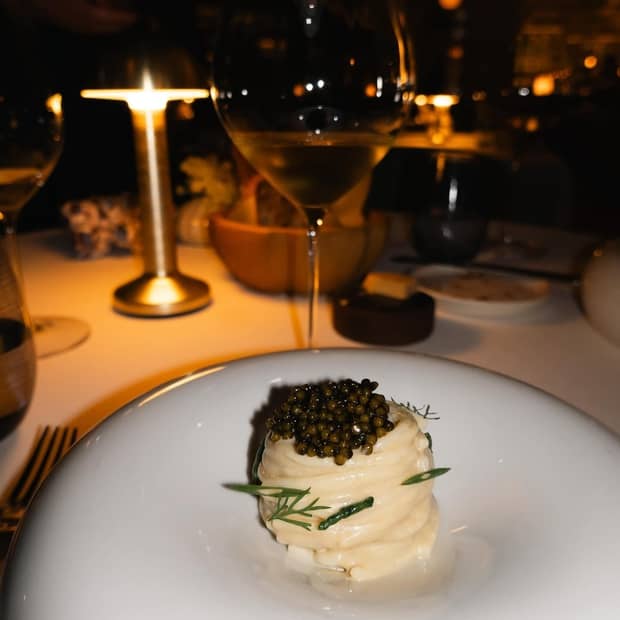 A table set with food and wine in softly illuminated surroundings.