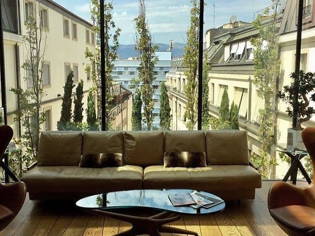 Sofa and coffee table in front of floor-to-ceiling glass wall with historic buildings in view