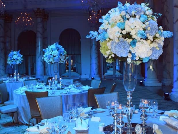 Wedding reception with round banquet tables, tall blue and white floral arrangements 