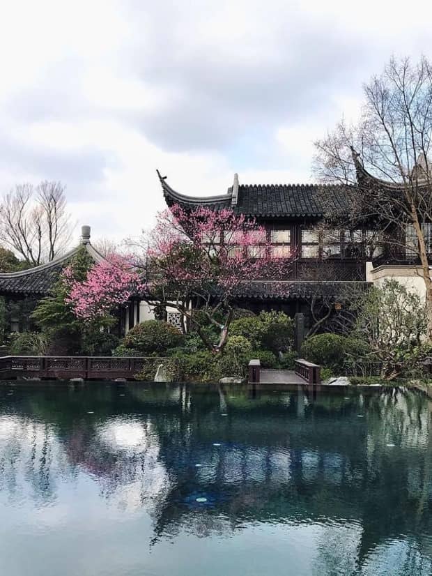 Four Seasons Hotel Hangzhou at West Lake building, trees reflected over pond