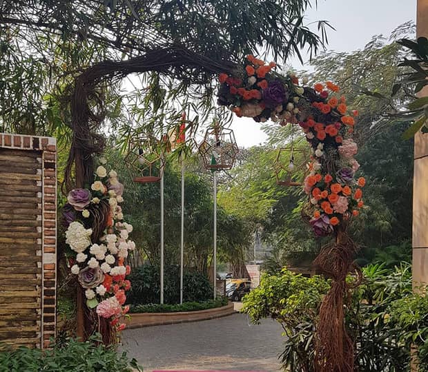 Rustic wedding archway with colourful flowers, near brick road and courtyard 