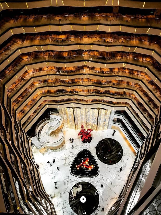 Looking down in open atrium past hotel floors to marble lobby, spiral staircase