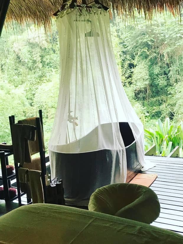 White net draped over freestanding bathtub under straw roof