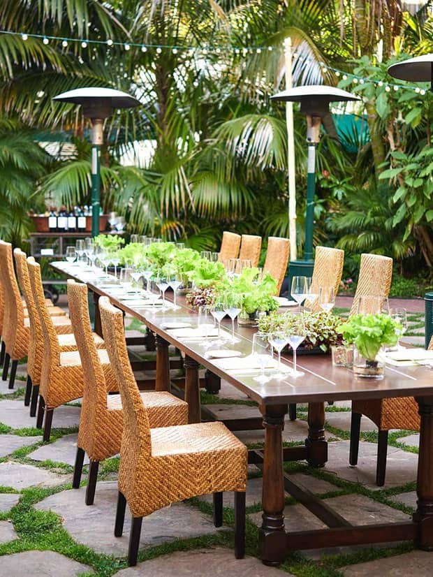 Garden patio long dining table with lettuce centrepieces and wicker chairs 