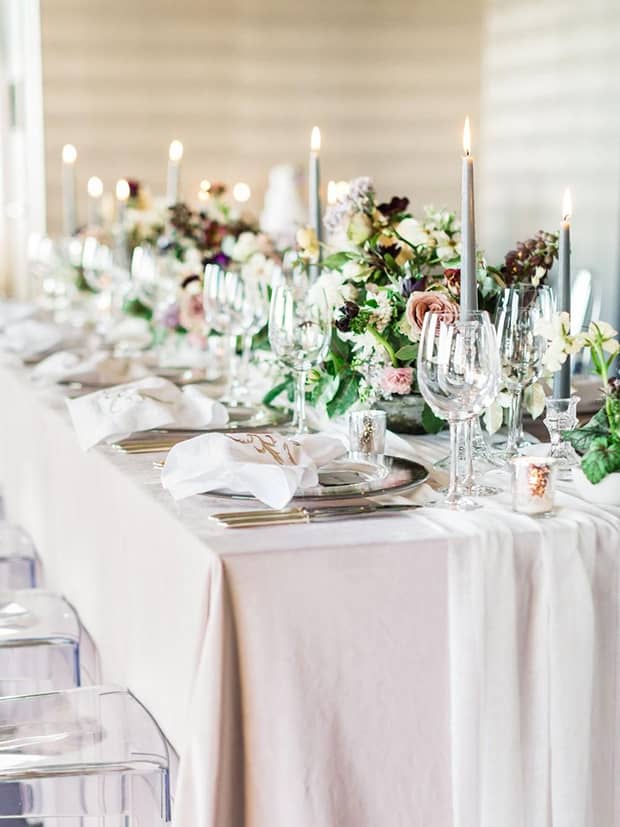 Elegant long wedding banquet table with tall candles, flowers 