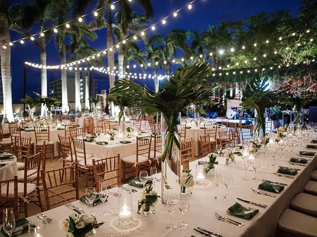 Outdoor banquet at night with patio lights strung over dining tables 