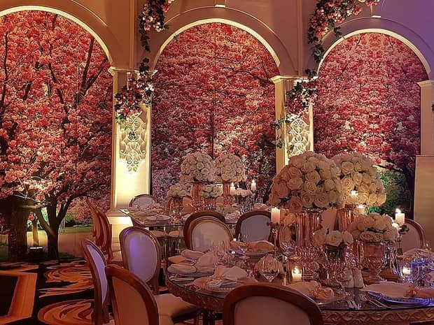 Banquet room with dining tables with roses, accent walls with blooming trees, pink flowers 