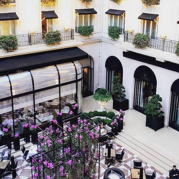 View over hotel atrium, guests around dining tables, purple flowers