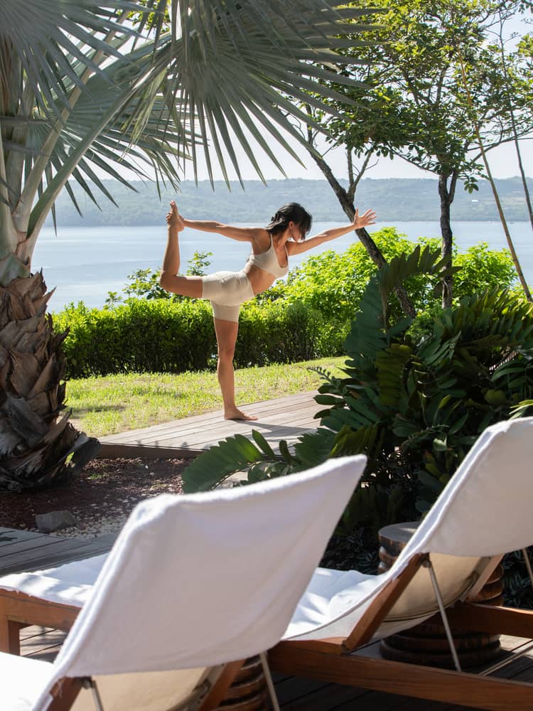 Person does yoga on an ocean-view lawn