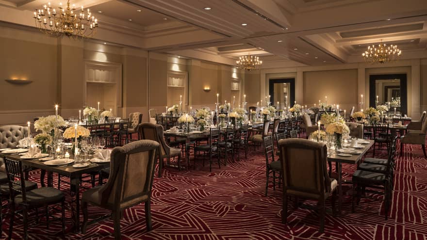 Wedding reception, dining tables with tall candles and white flowers in banquet room