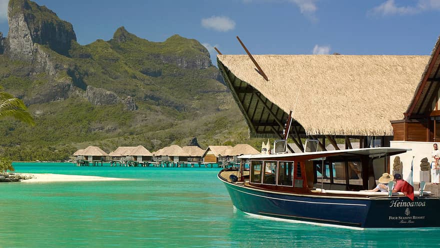 Boat on turquoise lagoon, overwater bungalows in the distance