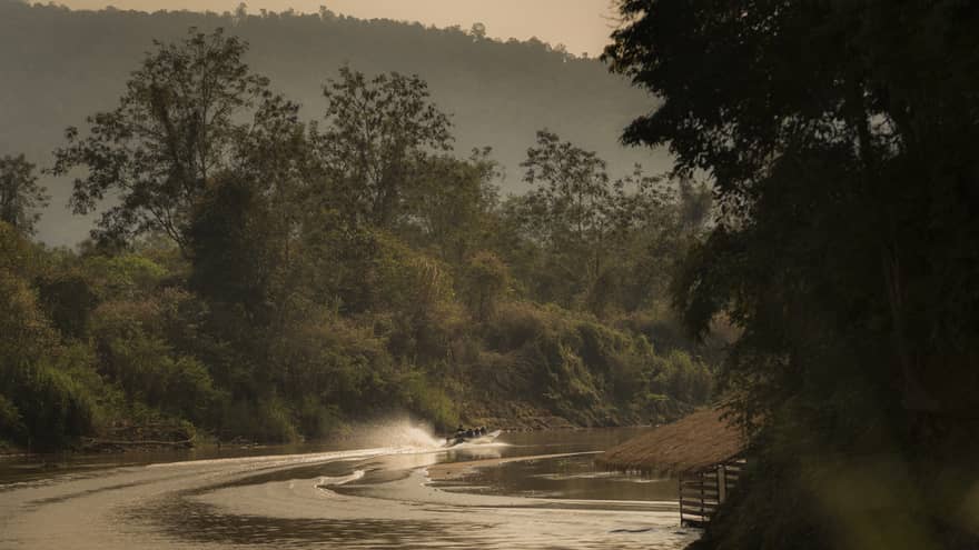 Longtail boat sprays water as it zips down the Ruak river