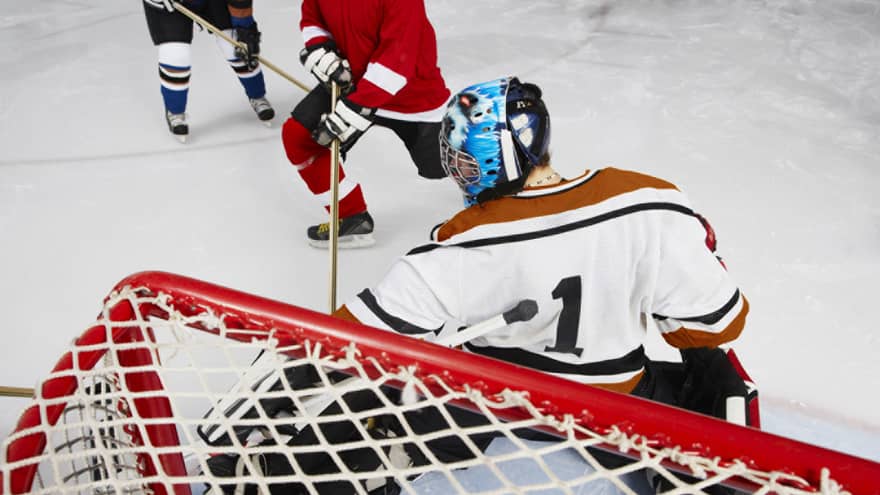Back view of hockey goalie in net blocking goal
