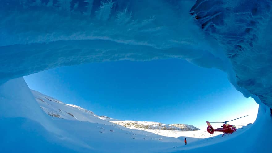 Helicopter against striking blue sky at opening of ice cave