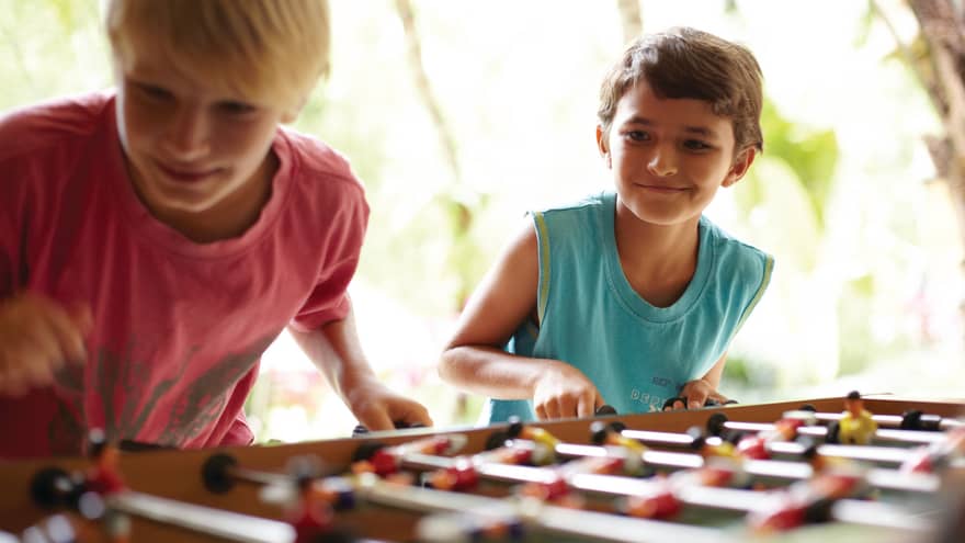 Two children smile while playing foosball